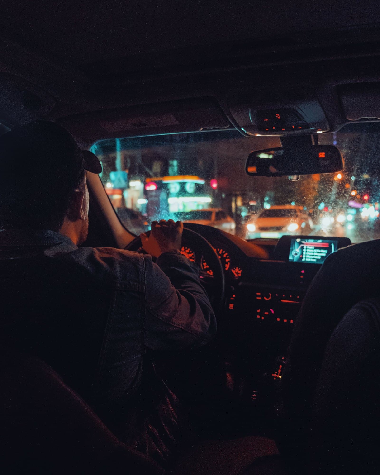 The view from the back seat at night: a driver steers through the city lights